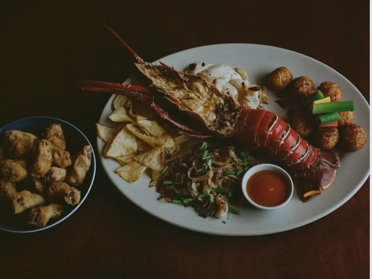 A whole grilled lobster and seafood on a platter with chips and fried dumplings