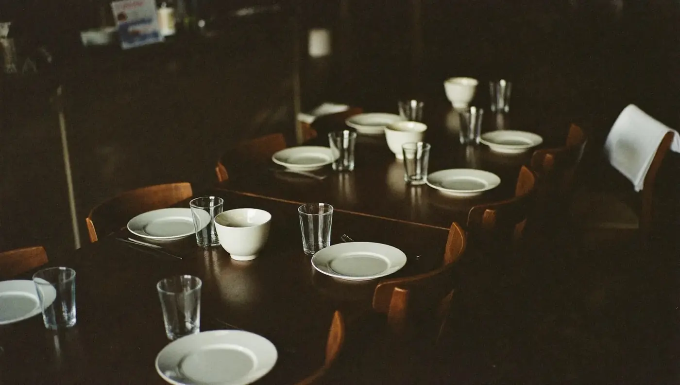 A long table set for several people in a small dining room, with the bar behind